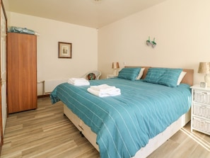 Une chambre à coucher avec un lit, une armoire en bois, un tableau encadré, une lampe et une table de chevet.