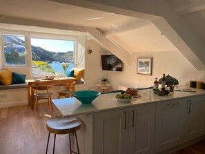 Eine Küche mit Meerblick, ein Essbereich mit Tisch und Stühlen sowie eine große Kochinsel mit einer Fruchtschale.