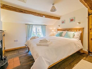 Un dormitorio con una cama de madera, una ventana con cortinas, una lámpara y una chimenea.