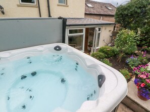 Ein Whirlpool in einem Garten mit einem Haus im Hintergrund.