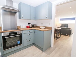 A compact kitchen with a built-in oven, a coffee maker, and a kettle on the counter. - 2 Dew Street, Menai Bridge (Menai Bridge)