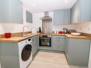 A compact kitchen with a washing machine, oven, and a sink. - 2 Dew Street, Menai Bridge (Menai Bridge)