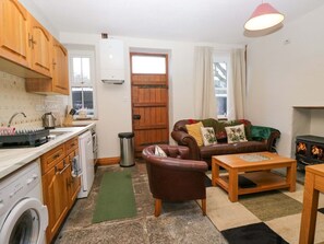 A compact living space with a kitchen, a sofa, a coffee table, and a fireplace. - 3 Mountain View is in Sedbergh (Sedbergh)