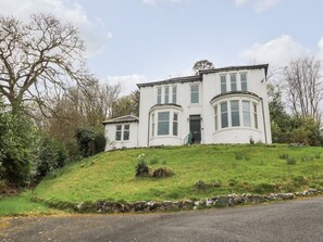 A two-story white building with a curved bay window, a front door, and a small porch.