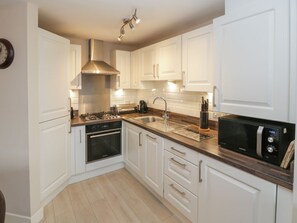 A modern kitchen with white cabinets, stainless steel appliances, and a wooden countertop. - Clickety-Clack Cottage, Whitby (Whitby)