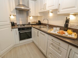 A modern kitchen with white cabinets, stainless steel appliances, and a wooden countertop. - Clickety-Clack Cottage, Whitby (Whitby)