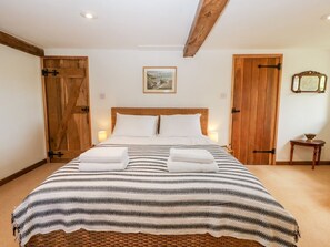 Ein Schlafzimmer mit einem großen Bett, Holztüren, einem gerahmten Bild an der Wand und einem kleinen Tisch mit einer Schale.