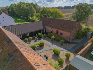 A courtyard with a brick building, a white building, and a field in the background. - Pear Tree, Wood Norton (Dereham)