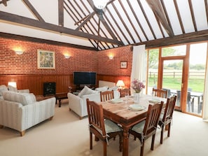 A dining area with a wooden table set for six, surrounded by chairs. - Pear Tree, Wood Norton (Dereham)