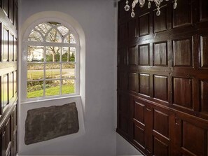 Ein Zimmer mit einer großen Holztür, einem Fenster mit Gartenblick und einer Steinwand.