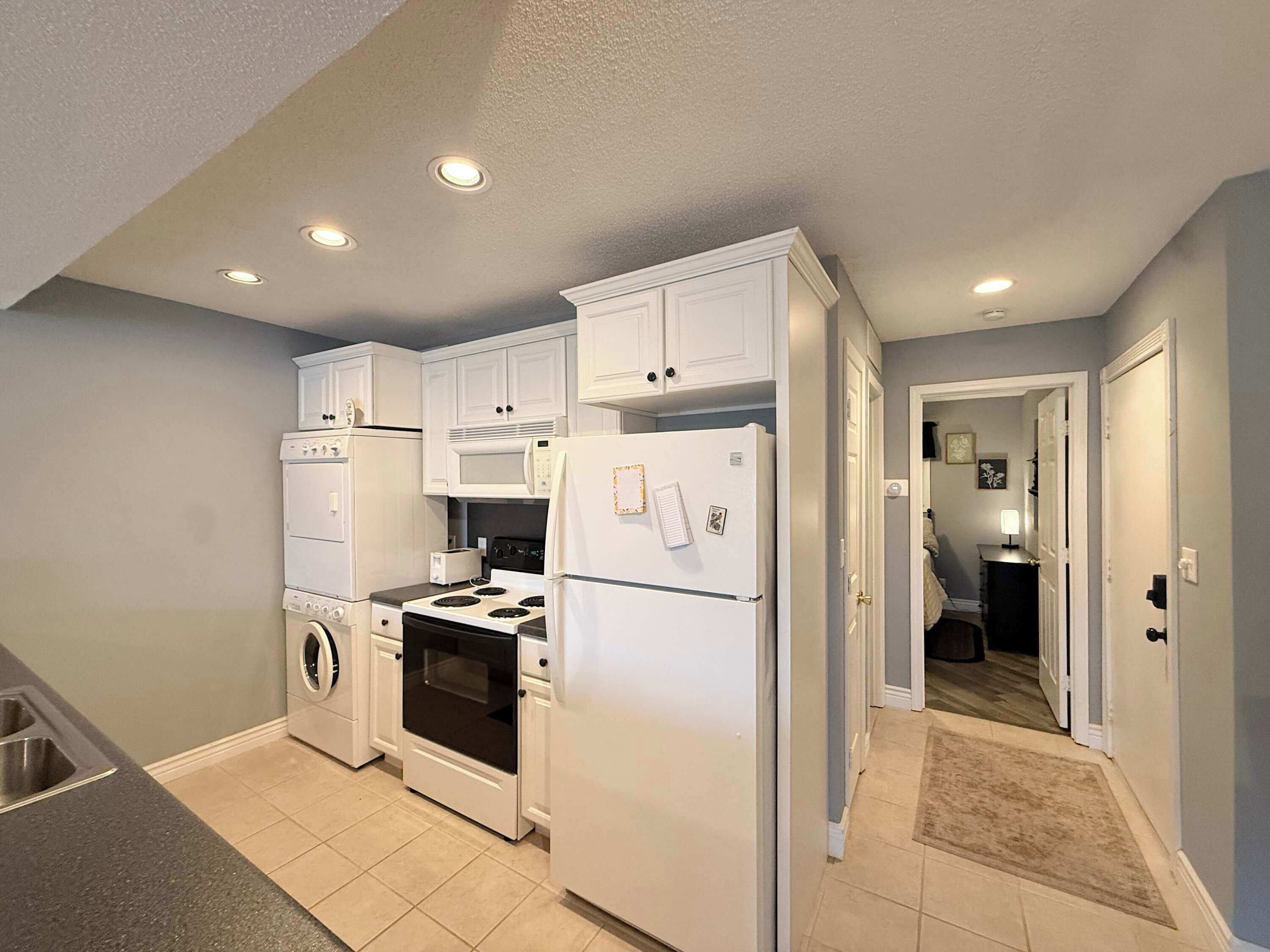 A compact kitchen with white appliances, a washing machine, and a microwave.