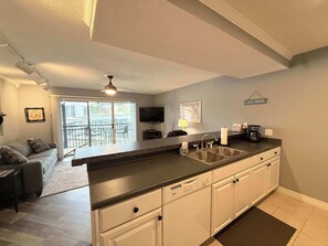 A modern kitchen with a large island, a dining area with a sofa and chairs, and a balcony with a view. - Harbor Hideout Waterfront (Osage Beach)