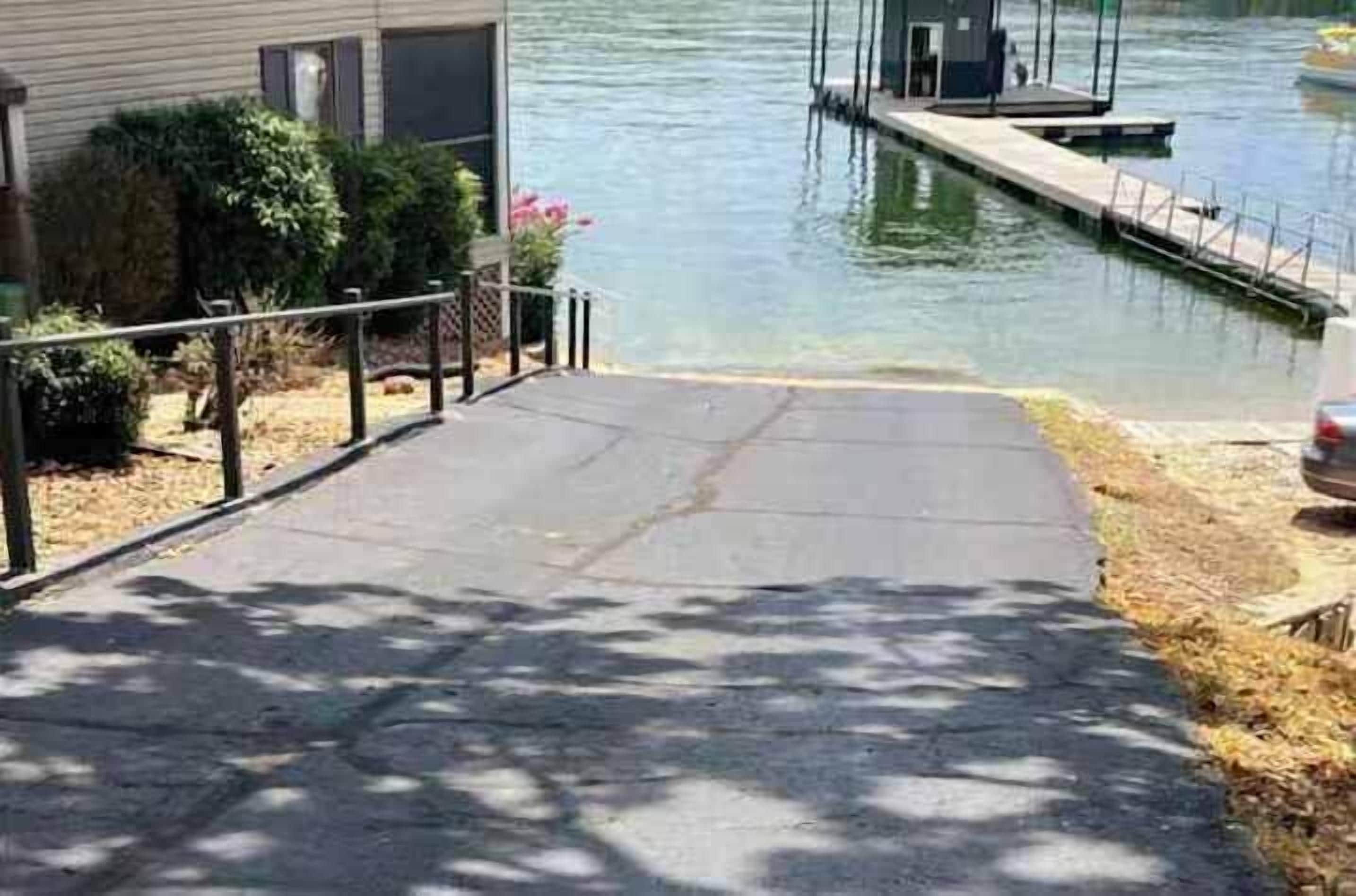 Um imóvel residencial com um cais que se estende sobre a água, um caminho de acesso pavimentado e um pequeno barco atracado no píer.