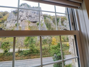 Una ventana con vistas a un acantilado rocoso y una carretera.