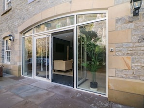 A building entrance with a glass door, a potted plant, and a stone wall.