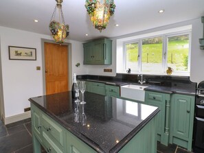 A kitchen with green cabinets, a black granite countertop, and a chandelier. - Thistlewood House, Wolsingham. (Bishop Auckland)