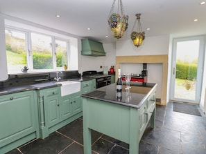 A kitchen with a central island, a built-in oven, and a window overlooking a garden. - Thistlewood House, Wolsingham. (Bishop Auckland)