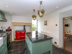 A kitchen with a central island, a red stove, and hanging light fixtures. - Thistlewood House, Wolsingham. (Bishop Auckland)