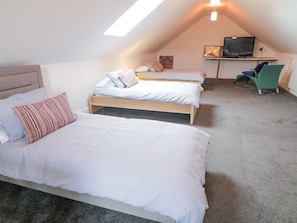 Une chambre avec deux lits, une télévision et un bureau.