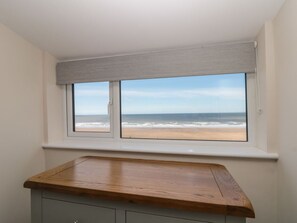 Ein Zimmer mit Blick auf den Strand, durch ein Fenster mit Holzbrettchen.