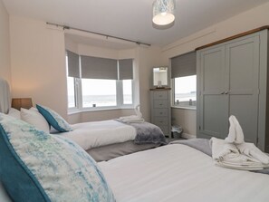 Ein Schlafzimmer mit zwei Betten, einem Kleiderschrank, einem Spiegel und einem Fenster mit Aussicht.
