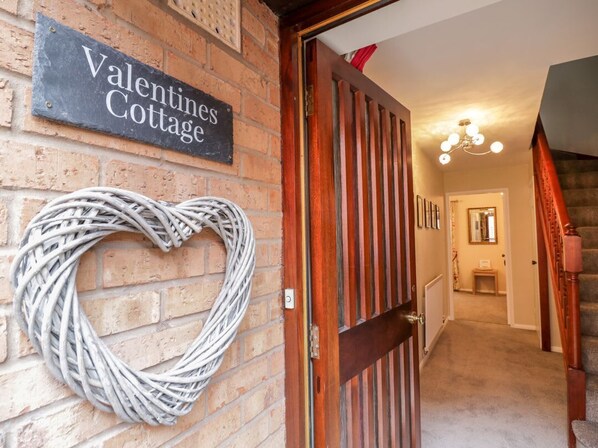 Eine Ziegelwand mit einem herzförmigen Kranz und einem Schild mit der Aufschrift 'Valentines Cottage'.