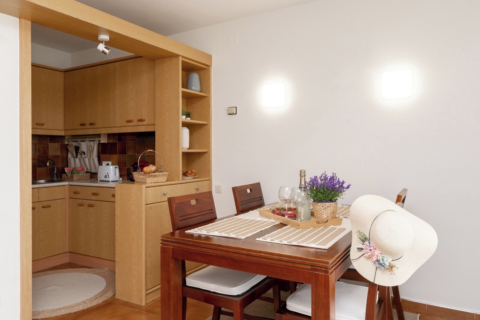 Ein Essbereich mit einem Holztisch, Stühlen, einer Ablage mit Speisen und Getränken und einer Küche im Hintergrund.