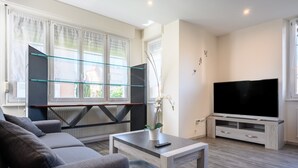 Een moderne woonkamer met een bank, televisie en een glazen schapunit.
