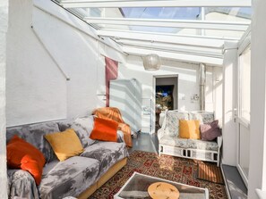 A sunlit room with a skylight, a sofa, a chair, and a patterned rug. - The Flat At Brwyn, Brynford (BRYNFORD)
