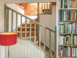 Eine Treppe mit einer roten Lampe, ein Bücherregal voller Bücher und ein Holzinnenausbau.