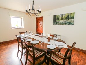 Ein Essbereich mit einem Holztisch, gedeckt für sechs Personen, umgeben von sechs Stühlen mit gestreiften Kissen.