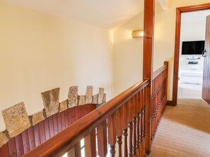 Eine Holztreppe mit Steindetails, die zu einem Zimmer mit einem Bett und einem Flachbildfernseher führt.