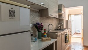 Una cucina moderna con lavastoviglie integrata, lavello e piano cottura. Sul muro è presente un codice QR e sul bancone c'è un vaso con fiori.