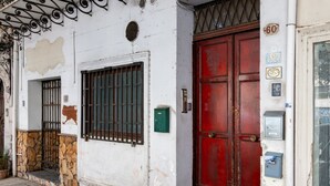 Un edificio con una porta rossa, una base in pietra e un muro bianco con la vernice che si scrosta.