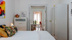 Una camera da letto con un letto, un comodino, una TV e una porta che dà su una sala da pranzo.