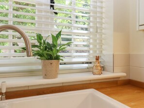 A kitchen with a white sink, a window with blinds, a potted plant, and a ceramic rabbit figurine on the windowsill. - Spindlewood Cottage, Hawkhurst (Cranbrook)