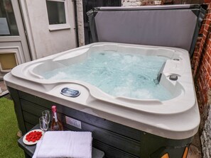 Ein Whirlpool mit Bedienfeld, eine Champagnerflasche, Gläser und eine Schale Erdbeeren.