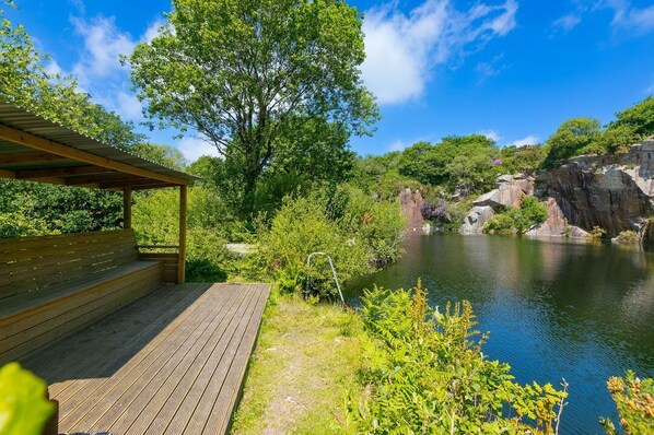 A wooden deck with a bench, a clear view of a river, and rocky cliffs in the background.