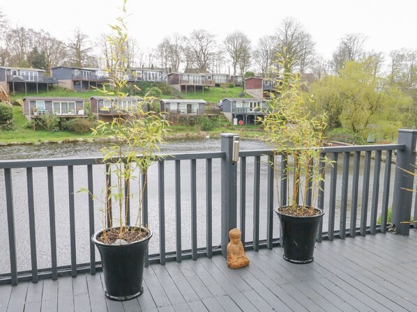 Una terraza de madera con plantas de bambú en macetas y una pequeña estatua de Buda.