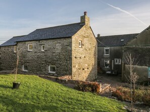 A stone building with a sloped roof, a chimney, and a small window. - The Granary Loft, Bardsea (Ulverston)