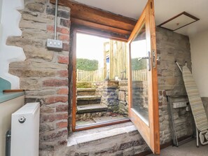 A room with a stone wall, a wooden door, a radiator, and a striped towel. - Castlewood Cottage, Skipton (Skipton)