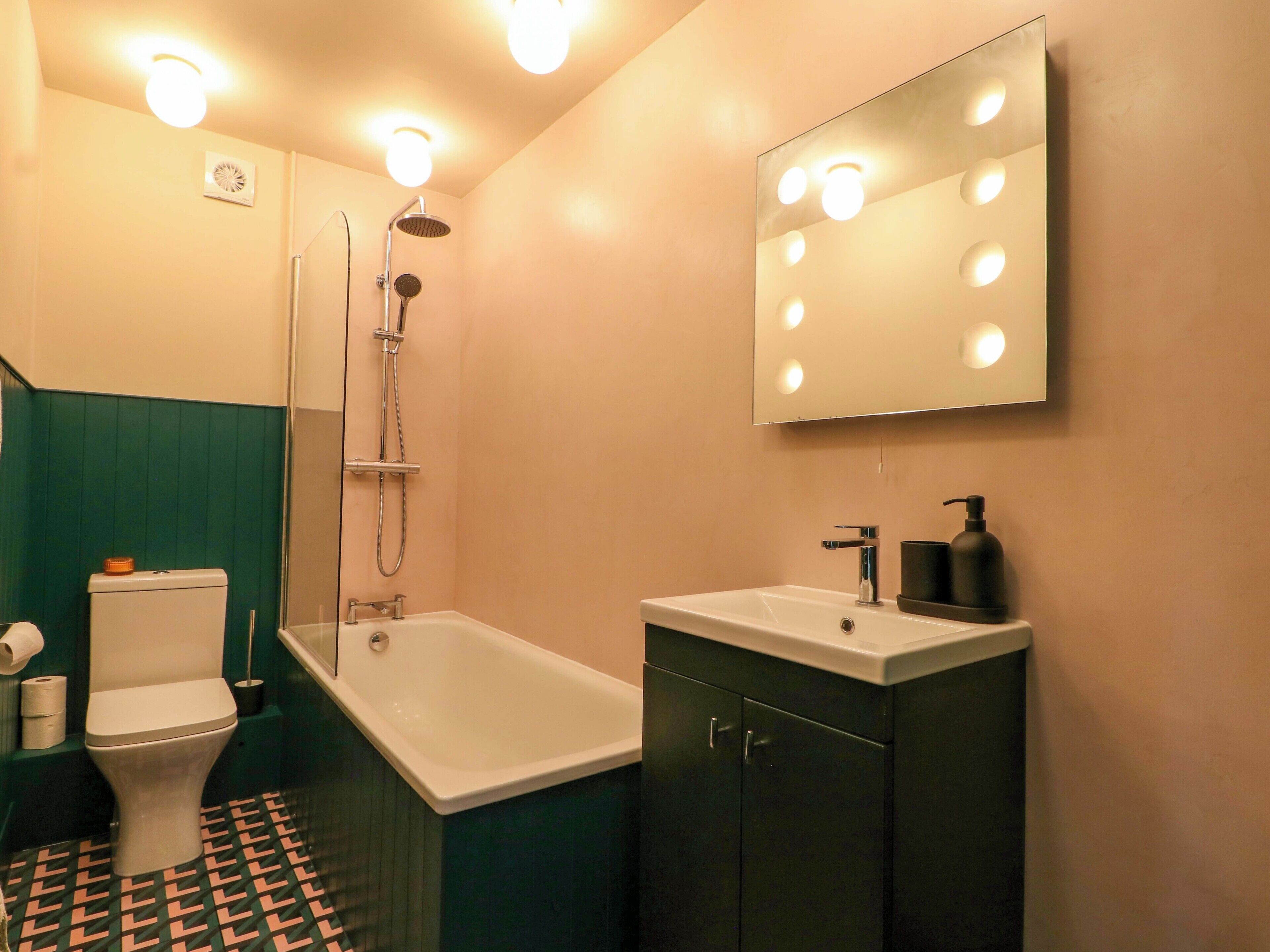 A bathroom with a toilet, shower, sink, and vanity.