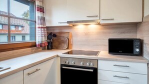 Une cuisine compacte équipée d’un four à micro-ondes, d’un four traditionnel et d’une fenêtre avec des rideaux.