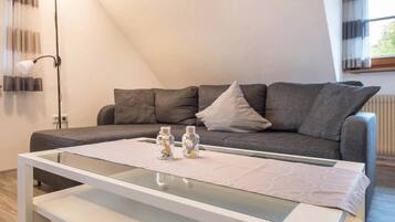 Un salon moderne avec un canapé gris, une table basse en verre et un lampadaire.
