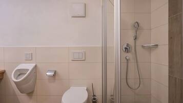 Een moderne badkamer met urinoir, toilet en douchecabine met glazen wanden.
