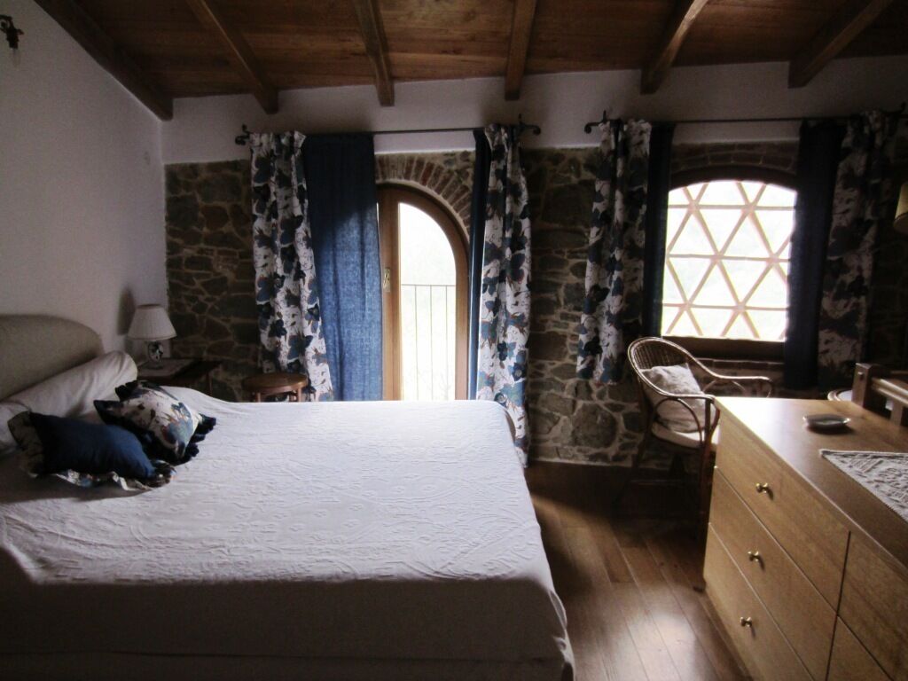 Un dormitorio con cama, cómoda, silla y pared de piedra.
