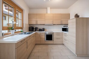 Une cuisine moderne avec des meubles en bois, un four encastré, un four à micro-ondes et une fenêtre offrant une belle vue.