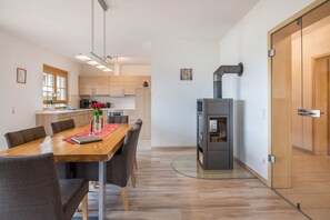 Une cuisine moderne dotée d’une cuisinière intégrée, de meubles en bois et d’un coin repas avec une table et des chaises.