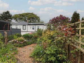 A garden with a gravel path, various plants, and a wooden fence. - Rosalin Cottage near to Irvine (Irvine)