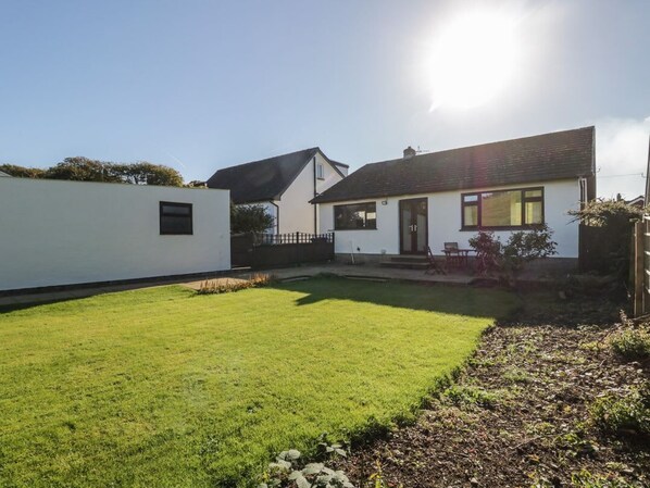 A residential property with a well-maintained lawn, a small patio area, and a white exterior wall.